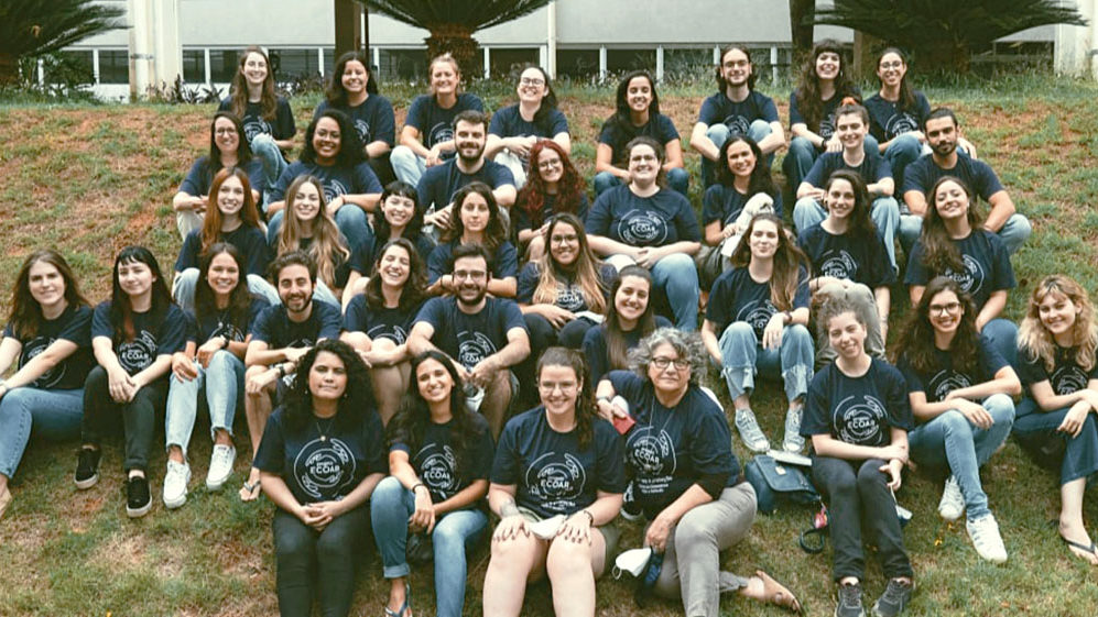 Dezenas de profissionais do Projeto Ecoar sentados em um gramado